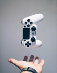 A hand holding a Playstation 5 controller